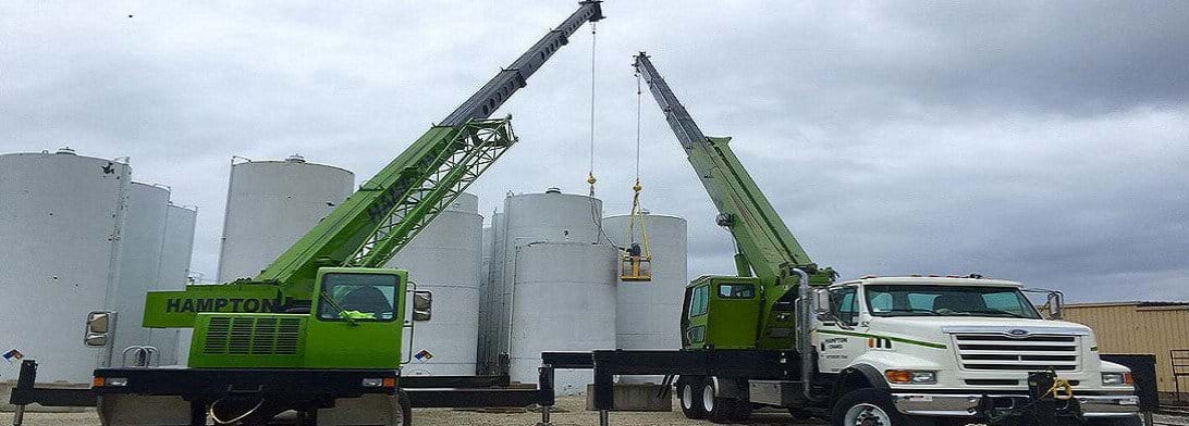 Two cranes being used in front of cement silos
